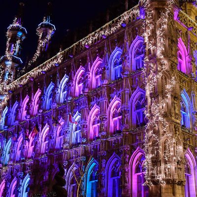 With light greenery garlands and string lite decorated facade of the gothic townhall in the city of Leuven, Belgium.