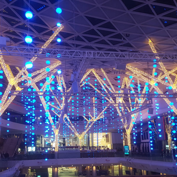Color changing light deco balls hanging from the ceiling and with drape lite decorated columns of the shopping center Westfield London in the city of London, United Kingdom.