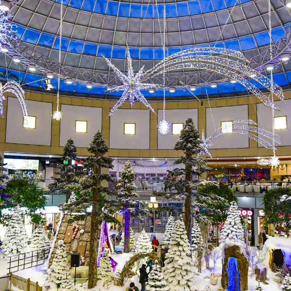 Light motifs of shooting stars and snow crystalls hanging from the ceiling above a grotto with a gingerbread house in a snowy forrest in the shopping center Allee-Center in the city of Leipzig, Germany.