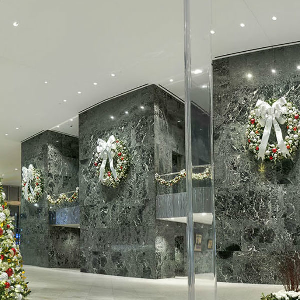 With silver and red deco baubels and a silver bow decorated wreaths and christmas tree in the lobby of Fisher Brothers 55 east 52nd street building in the city of New York, United States of America.