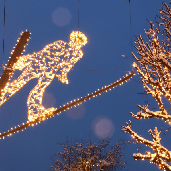 Close up view of light sculpture of a ski jumper hanging above the streets for the FIS nordic ski world cup in the city of Seefeld, Austria.