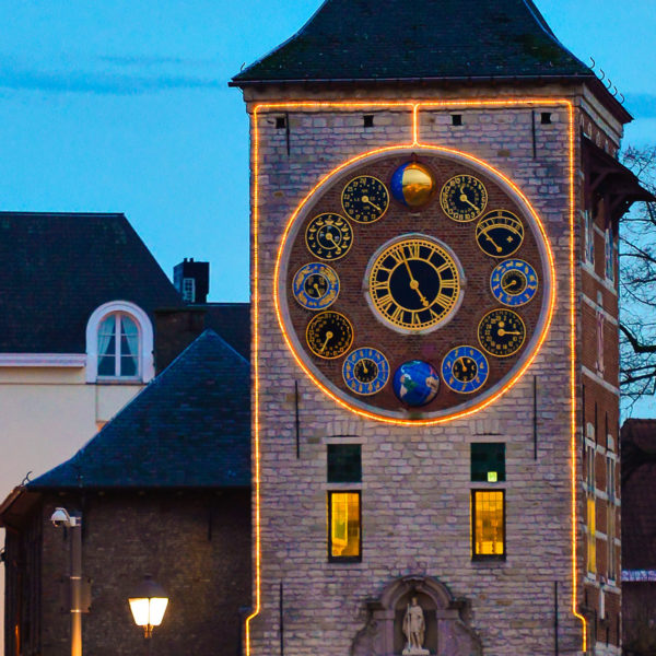 With warm white string lite accentuated "Zimmerturm" clock tower in the city of Lier, Belgium.